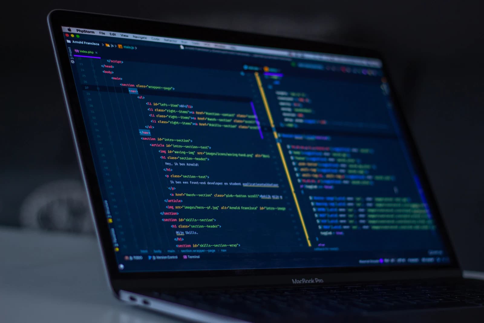 Laptop on a desk showing website code in a dark-themed editor