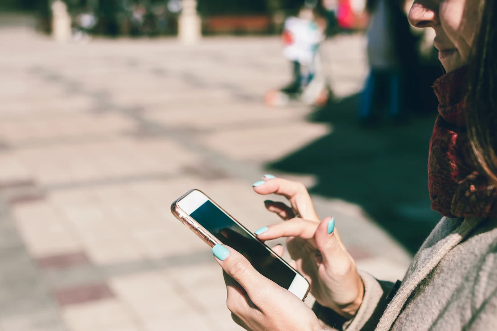 Woman scrolling on a smartphone outdoors on a sunny day
