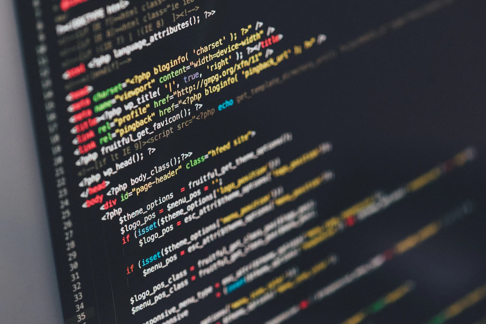 Close-up of colourful source code on a dark computer monitor