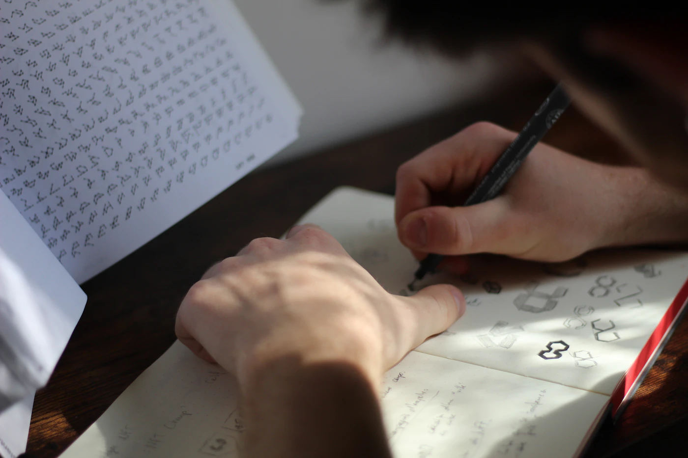 Designer sketching logo concepts in a notebook with a black pen