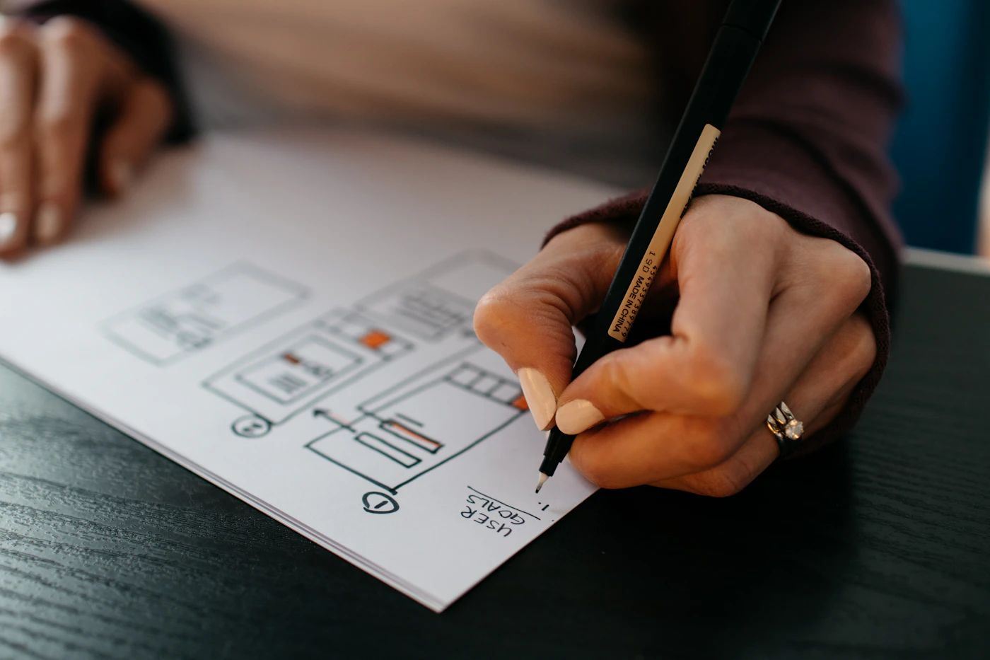 Designer sketching a landing page wireframe with a pen on paper