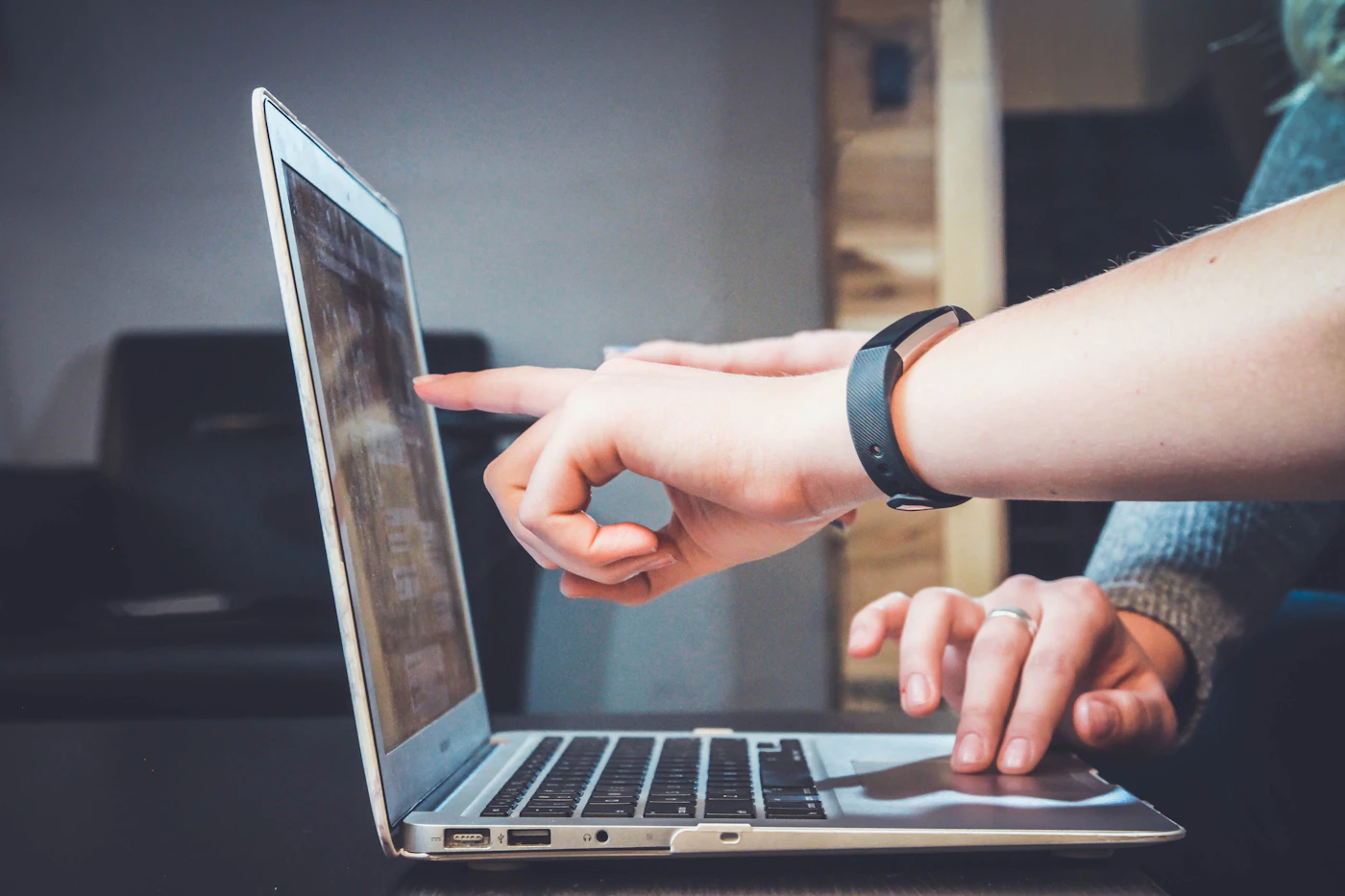 Two people at a laptop, one pointing at the screen while discussing a list